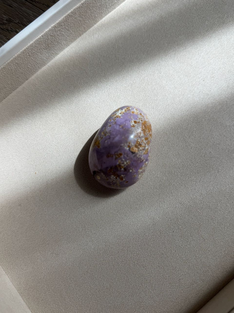Phosphosiderite palm stone in soft lavender with golden veining, in a white tray