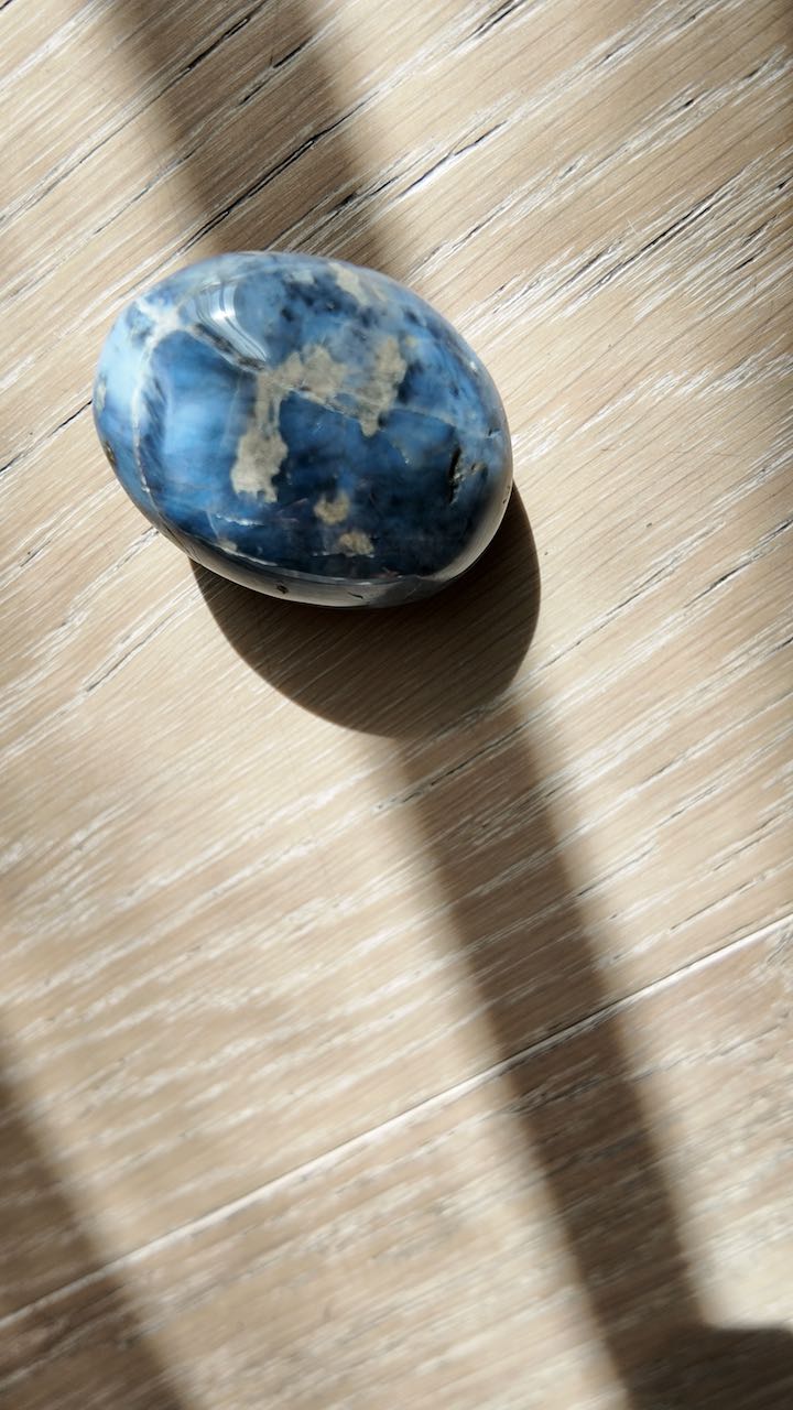 A cloud-blue quartz palm stone in a band of morning light