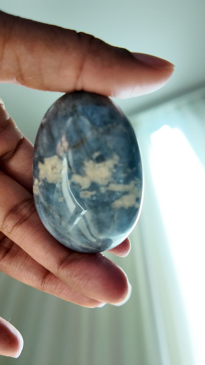 Blue quartz palm stone held to the window, catching the light