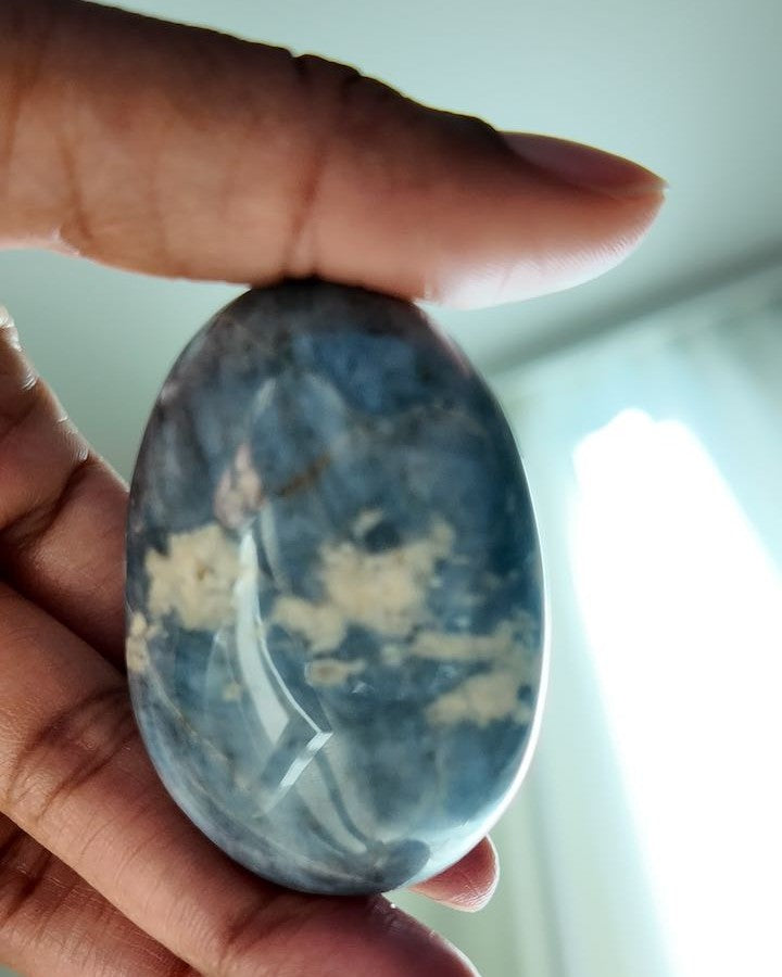 LIT FROM WITHIN blue quartz palm stone held in hand