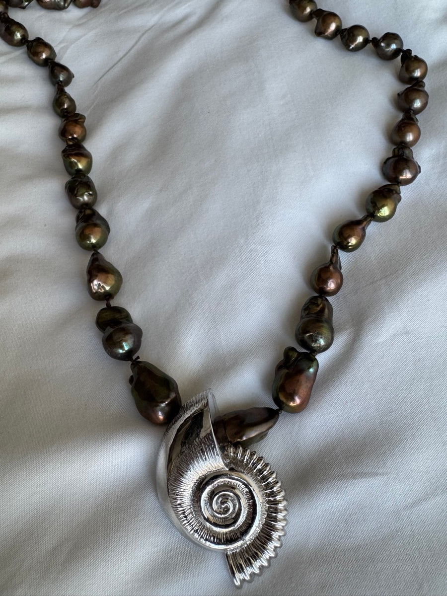 NIGHT SWIM close-up, the ribbed spiral shell against chocolate baroque pearls
