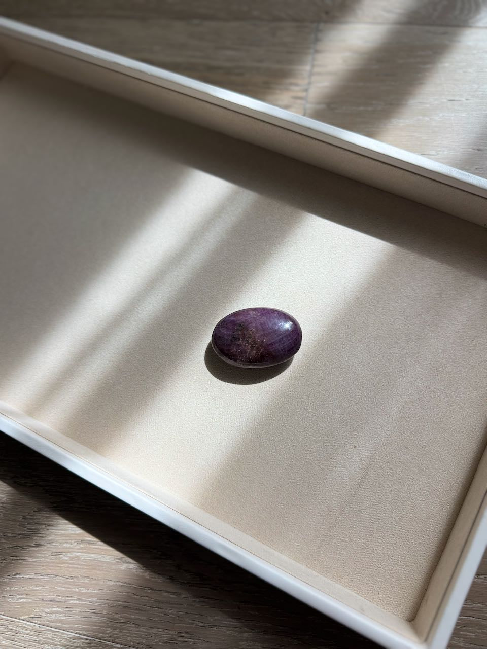 The ruby palm stone in raking light, showing its weight in the hand